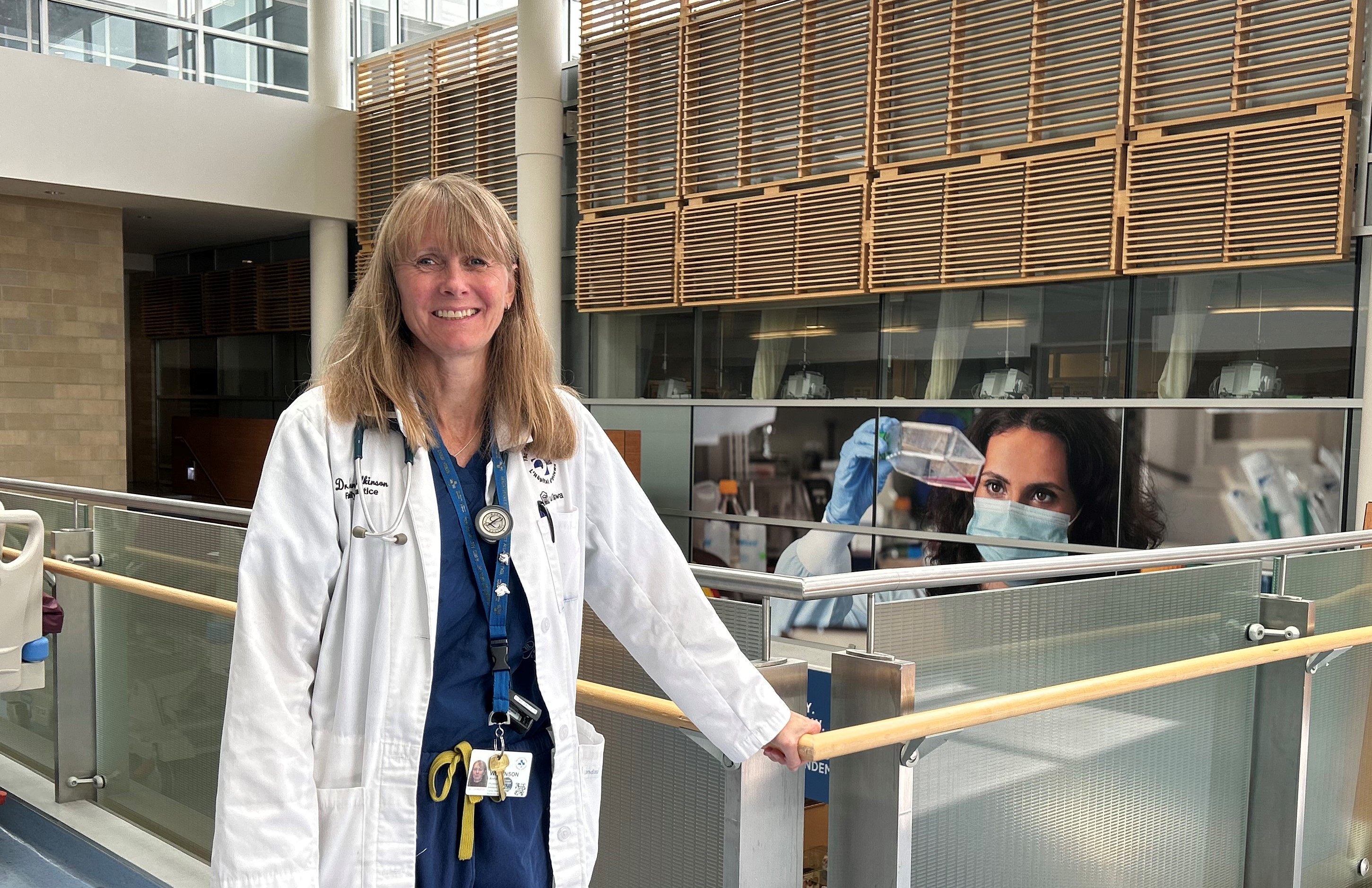 woman in lab coat stands in hospital hallway